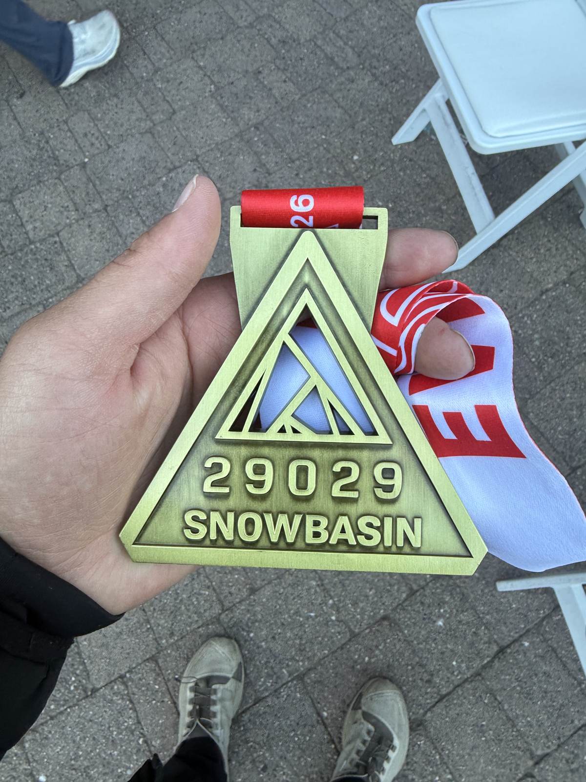 The 29029 Snowbasin finisher medal, a brass triangle, held in his hand