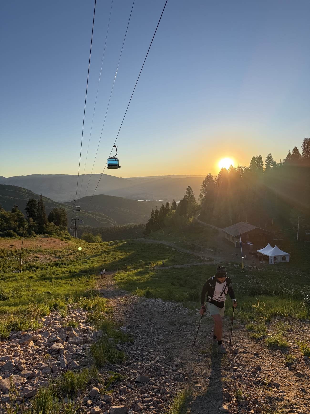 Sunrise over the ridge at Snowbasin with a climber ascending the trail and the gondola line overhead