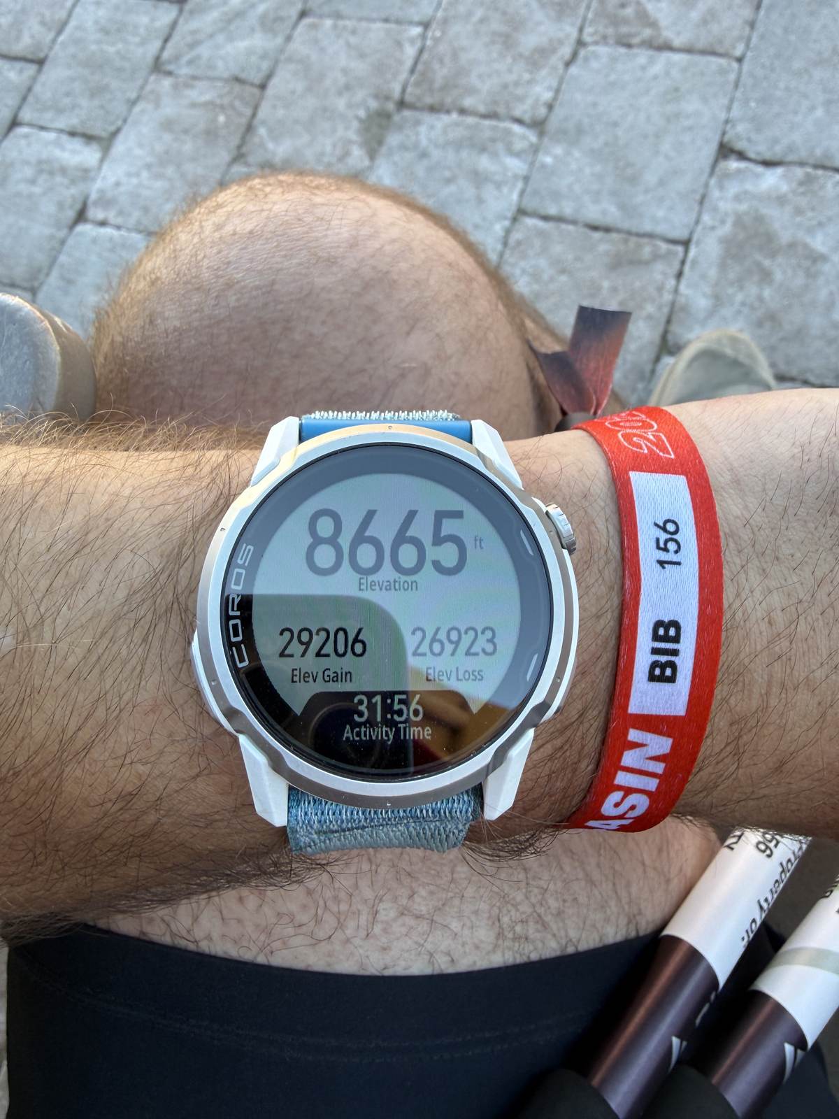 COROS watch face reading 29,206 ft elevation gain and 31:56 activity time, next to the red BIB 156 wristband